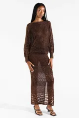 Falda midi tejida con diseño calado y abertura frontal, color marrón con hilos metalizados dorados.