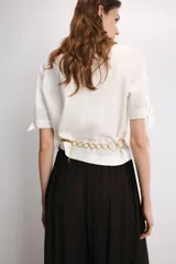 Camisa de manga corta confeccionada en tejido de ramio color blanco. Posee cuello solapa, cierre frontal con botones y detalle de lazos en el acabado de las mangas.