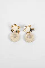 Aros colgantes con diseño floral y circular, compuestos por una flor metálica dorada con centro de hilo tejido y un aro inferior de fibra natural tejida.