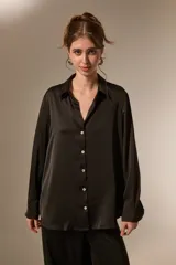 Camisa de poliéster con acabado satinado, de corte holgado, cuello camisero clásico, cierre frontal con botones y mangas largas con puños.