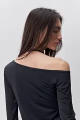 Remera de manga larga negra con calce al cuerpo y escote amplio tipo bote que deja los hombros al descubierto.