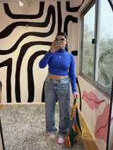 Polera de manga larga, cuello alto y corte crop, color azul Francia, confeccionada en lycra premium con un pequeño logo bordado en color rosa en el pecho.