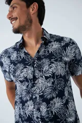 Camisa de manga corta con estampado botánico de hojas en tonos azul y blanco. Presenta cuello clásico, cierre frontal abotonado y corte slim.