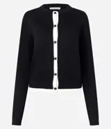 Cardigan de punto Marfinno, color negro con detalles en blanco en la botonera y el ruedo. Presenta cuello redondo, mangas largas y cierre frontal con botones oscuros.