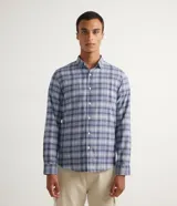 Camisa de franela de manga larga con estampado de cuadros en tonos azul y gris. Tiene cuello camisero y cierre frontal con botones.