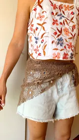 Pañuelo de crochet color marrón con diseño calado, versátil para usar como accesorio en la cintura o en el cuello.