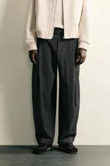 Pantalón de corte balloon fit confeccionado en tejido con viscosa. Presenta cintura ajustable con cinturón integrado, pliegues frontales, bolsillos laterales y bolsillos traseros de doble vivo. Cierre frontal con cremallera y botón.