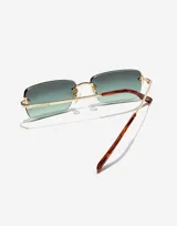 Lentes de sol rectangulares al aire con cristales degradados en tono verde. Presentan una estructura metálica dorada con patillas finas y terminales en carey.