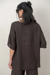 Blusa de lino color beige, de calce cómodo y relajado, con cuello redondo, mangas cortas y detalle de alforzas y guarda bordada en el lateral.