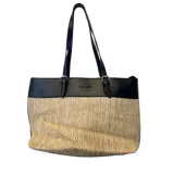 Cartera tipo tote de diseño bicolor, con la parte superior en cuero sintético negro y la parte inferior en tejido de fibra natural tipo rafia. Cuenta con doble asa de hombro ajustable con hebillas metálicas y logo de la marca grabado en el frente.