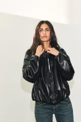 Chaqueta bomber de efecto piel con cuello solapa, cierre frontal de cremallera metálica, bolsillos laterales de vivo y bajo y puños con elástico.