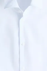Camisa de vestir H&M de corte entallado, confeccionada en tejido elástico de mezcla de algodón. Presenta cuello italiano, cierre frontal de botones y mangas largas con puños ajustables.