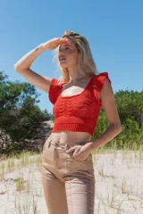 Top tejido de punto con lurex, color naranja, de escote redondo y mangas cortas con volados. Presenta un diseño corto con cintura acanalada.