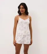 Pijama short doll de dos piezas en color blanco con estampado de ositos cariñositos y estrellas rosadas. Está compuesto por una musculosa de escote en V con tirantes finos y detalle de moño, y un short con cintura elástica y bordes ondulados.