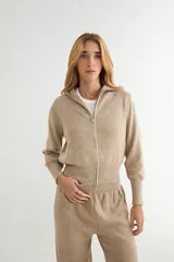 Conjunto de dos piezas tejido en color crema, compuesto por un cárdigan con cierre frontal completo y cuello alto, y pantalón de corte recto con cintura elástica.