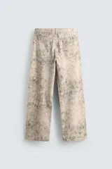 Pantalón de corte baggy fit confeccionado en tejido de algodón con efecto lavado y estampado abstracto en tonos beige y gris. Presenta diseño de cinco bolsillos, cierre frontal con cremallera y botón.