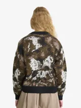 Cardigan de punto con diseño abstracto en tonos marrones, negros y blancos. Presenta cuello en V, cierre frontal con botones y terminaciones acanaladas en puños y ruedo.