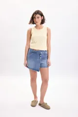Short pollera de mezclilla en color azul, con diseño cruzado al frente y cierre de botones metálicos.