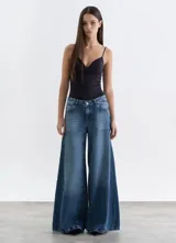 Jean de tiro medio con corte wide leg extra ancho, confeccionado en denim azul con efecto lavado y costuras laterales destacadas.