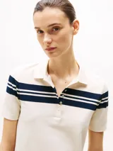 Chomba blanca de piqué de algodón elástico con rayas horizontales azul marino en cuello y mangas, corte slim, cuello de chomba con tapeta de seis botones y logo de Tommy Hilfiger bordado en la manga.