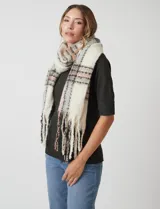 Bufandón de tejido soft, color crema con patrón a cuadros en tonos rosa pálido, gris y negro. Presenta terminación con flecos.