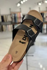Sandalia marrón con diseño de dos tiras ajustables con hebillas metálicas y plantilla anatómica.