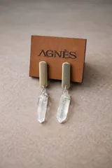 Aros colgantes con base dorada y dije de cristal transparente en forma de piedra.