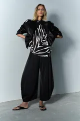 Sandalia plana tipo ojota de piel color negro, con tira ancha que sujeta el pie y tira central para el dedo.