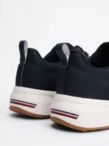 Zapatillas Tommy Hilfiger de running, color azul marino, con exterior de punto y poliéster, suela de goma blanca y detalles distintivos de la marca en el talón.