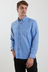 Camisa de vestir blanca de manga larga, con cuello abotonado, bolsillo frontal y botones en tono madera.