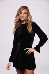 Vestido corto negro de terciopelo, con cuello alto y mangas largas acampanadas.