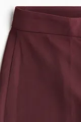 Pantalón sastrero de tiro alto, color bordó, con piernas amplias y pliegues marcados en el frente y la espalda.