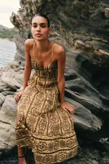Vestido midi de broderie en tonos mostaza y marrón, con escote en V, tirantes finos ajustables, abertura cut-out en la cintura y espalda con nido de abeja elástico.