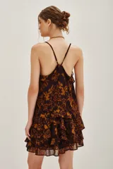 Top de tirantes finos con escote en V y detalle de volados en el borde. Presenta un estampado abstracto en tonos marrones y ocres, con un diseño fluido y ligero.