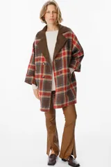 Blazer de corte relajado con estampado de cuadros en tonos marrones, rojos y azules. Presenta solapas de pana en color marrón chocolate, cierre frontal con botones y bolsillos laterales.