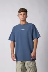 Remera oversize de algodón pesado color azul, con bordado "HUMAN" centrado en el pecho y hombros ligeramente caídos.