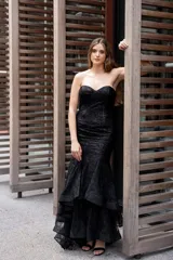 Vestido largo negro strapless tipo corset con tul y lentejuelas, de corte sirena y falda con volados.