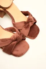 Sandalia de tacón cuadrado medio, confeccionada en terciopelo negro. Presenta un diseño de tiras cruzadas con nudo en la parte delantera y una tira ajustable con hebilla en el tobillo.