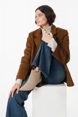 Bota de cuero color chocolate con diseño versátil que incluye una polaina desmontable. Presenta punta fina, taco cuadrado y un detalle bordado en la parte superior de la caña.