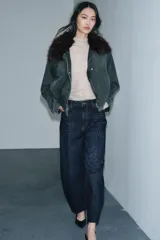 Chaqueta tipo bomber de denim lavado azul, corte holgado, con cuello solapa y aplicación de pelo sintético marrón desmontable. Presenta bolsillos delanteros y bajo acabado en elástico.