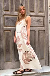 Vestido largo con fondo crudo y estampado de hojas marrones, corte recto con escote en V y breteles anchos.
