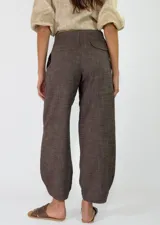Pantalón azul marino de tiro alto y corte ancho, confeccionado en tejido con textura sutil, bolsillos laterales y cierre frontal con botón.