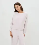 Conjunto de pijama compuesto por blusa de manga larga con cuello redondo y pantalón largo de corte regular. Confeccionado en plush suave, presenta detalles de encaje aplicados en los laterales de las mangas y de las piernas. El pantalón cuenta con cintura elástica para mayor comodidad.