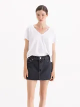 Minifalda de denim negro, de tiro medio/bajo y corte recto, con cinco bolsillos y ruedo desflecado al corte.