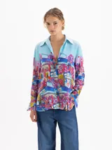 Camisa de seda con cuello clásico, manga larga y cierre frontal con botones ocultos. Presenta un estampado artístico colorido con motivos urbanos y naturales de la cápsula Il Bunny Porta Fortuna.