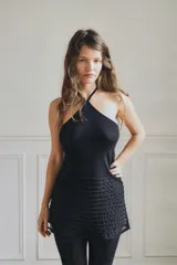 Top negro con cuello halter ajustable mediante lazo. La parte superior es opaca y ajustada, mientras que la parte inferior presenta un tejido semitransparente con franjas horizontales en relieve.