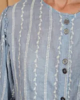 Camisa de manga larga con diseño de rayas verticales y bordados sutiles. Presenta cuello redondo, cierre frontal con botones y mangas abullonadas con volados en los hombros.