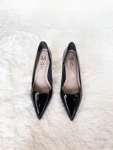 Zapatos de tacón alto con textura de reptil, color negro, con suela roja característica.