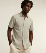 Camisa de manga corta confeccionada en mezcla de lino y algodón, con cuello inglés, cierre frontal de botones y bolsillo en el pecho. Presenta un corte comfort holgado y diseño liso.