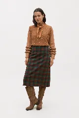 Falda midi de corte recto con estampado de cuadros en tonos marrones y verdes. Presenta un diseño estructurado y elegante, confeccionada en tejido de lana con forro interior.